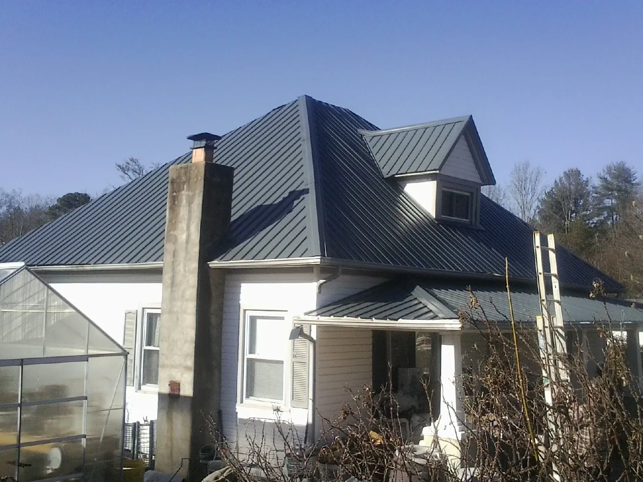 Dark blue standing seam metal roof on a white farmhouse with dormer — Slate & Tile Roof Repair by Roofing Brothers in Edmonds
