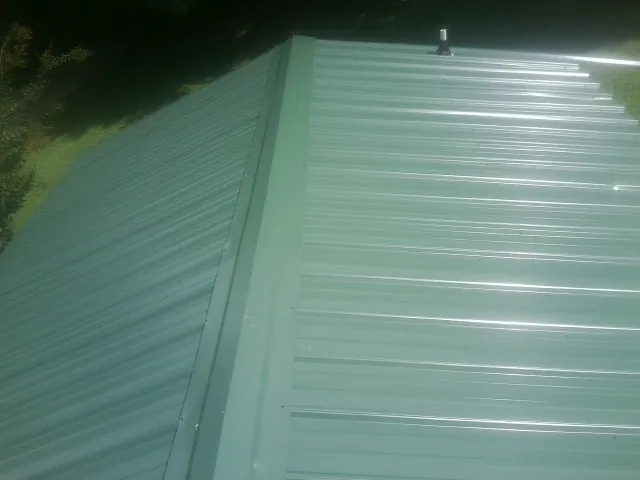 New green metal panels meeting at the ridge of a roof — Flat Roof Repair work by our crew in Edmonds