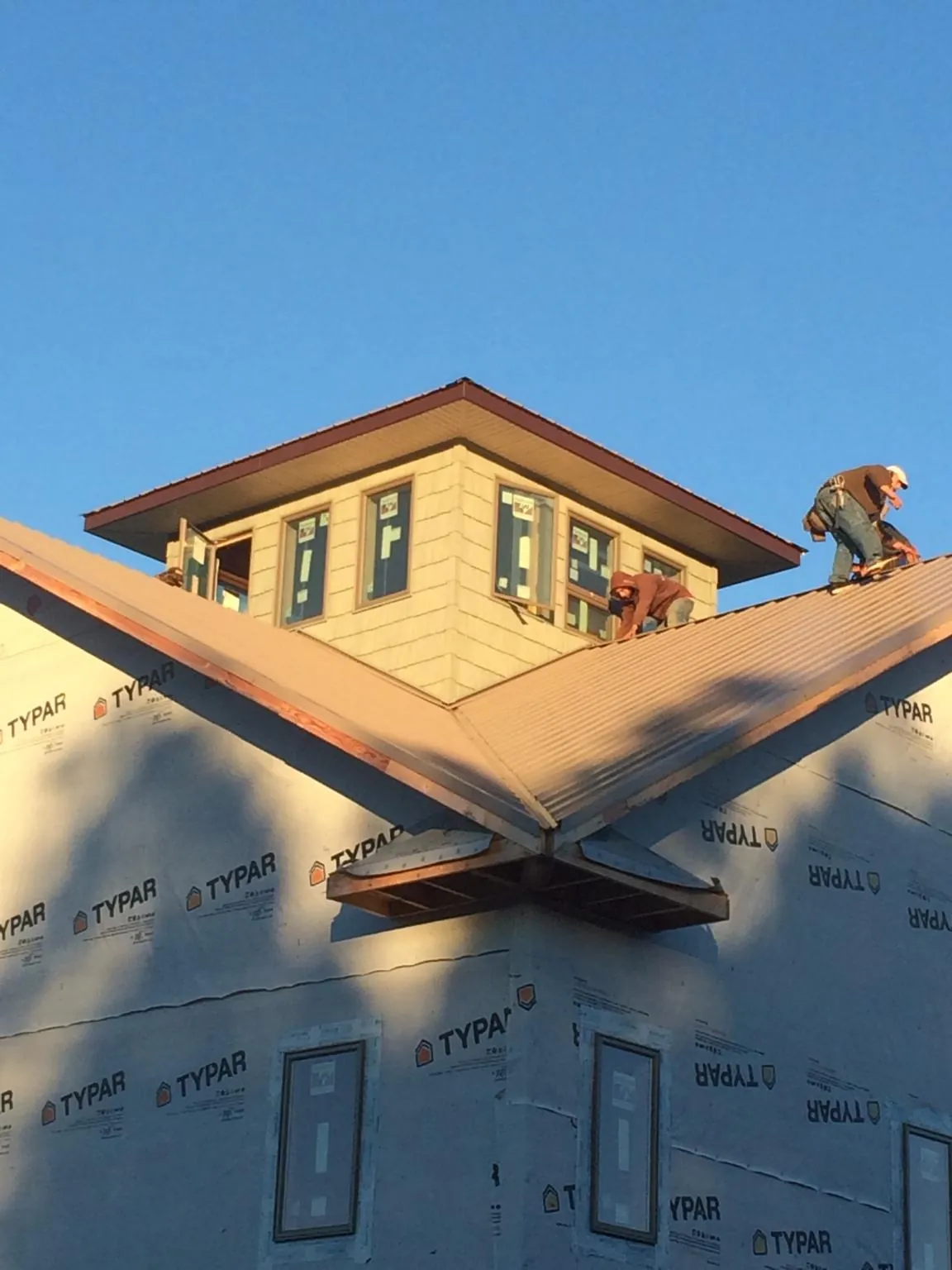 Roofers working around a rooftop cupola on a new metal roof at sunset — Roof Waterproofing in Edmonds by Roofing Brothers